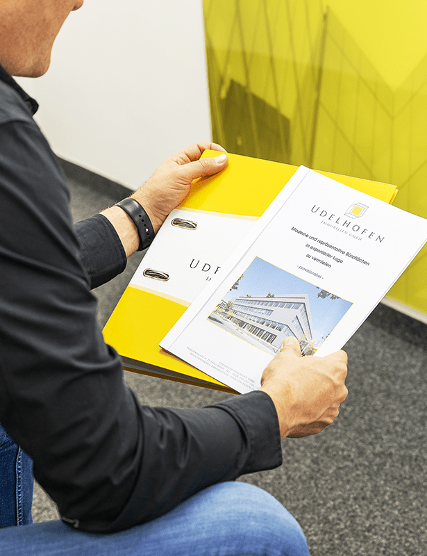 Person hält gelben Aktenordner mit Broschüre.