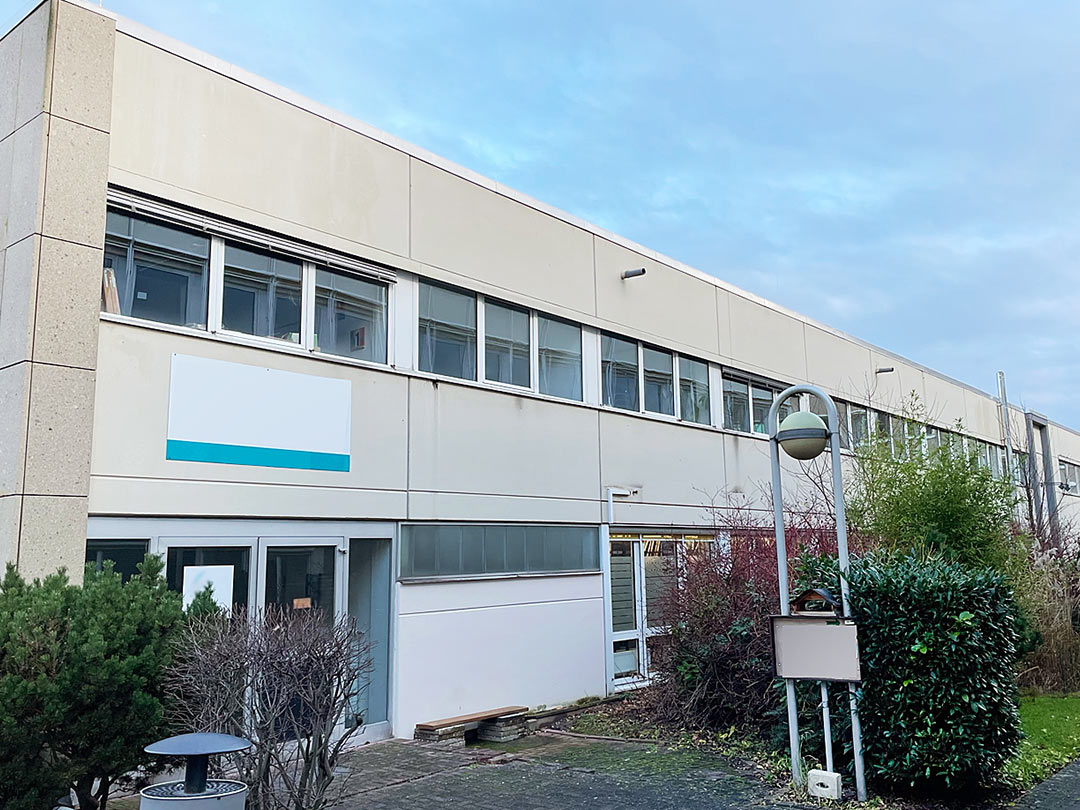 Modernes Gebäude mit großen Fenstern und weißer Fassade.