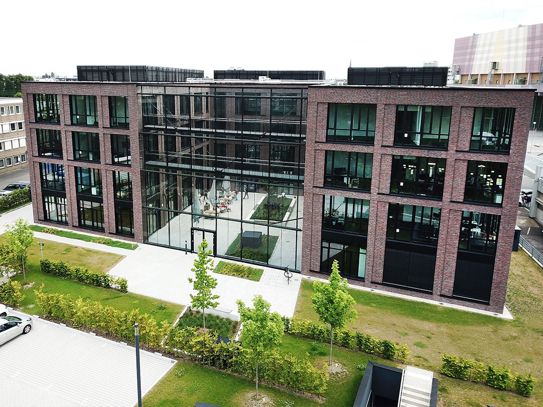 Modernes Gebäude mit Glasfassade und Grünanlagen