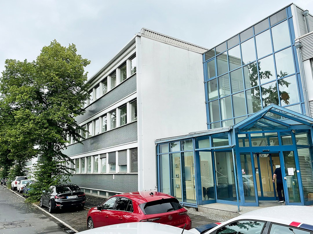 Modernes Gebäude mit Glasfassade und geparkten Autos.