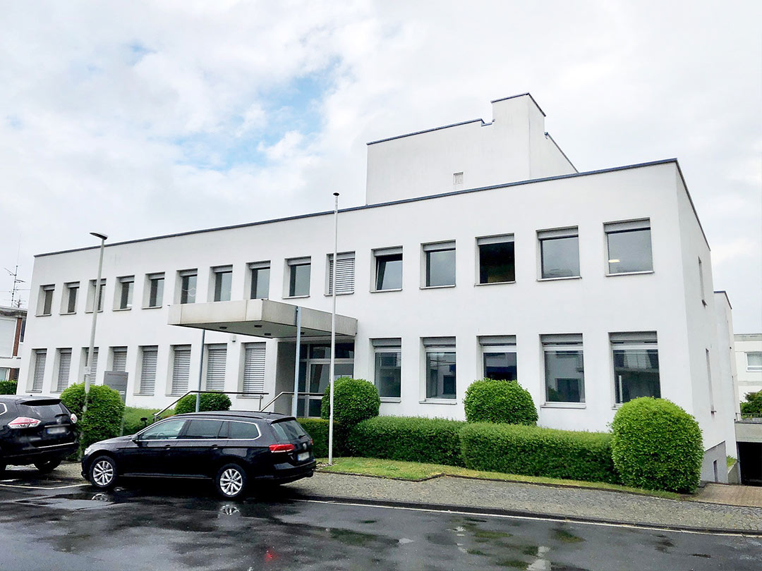 Modernes weißes Gebäude mit Autos davor