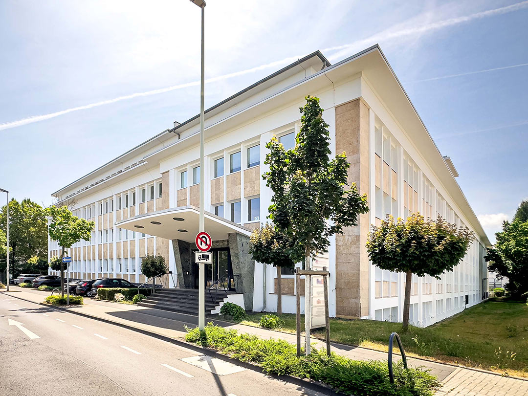Modernes Bürogebäude mit Bäumen und blauer Himmel.