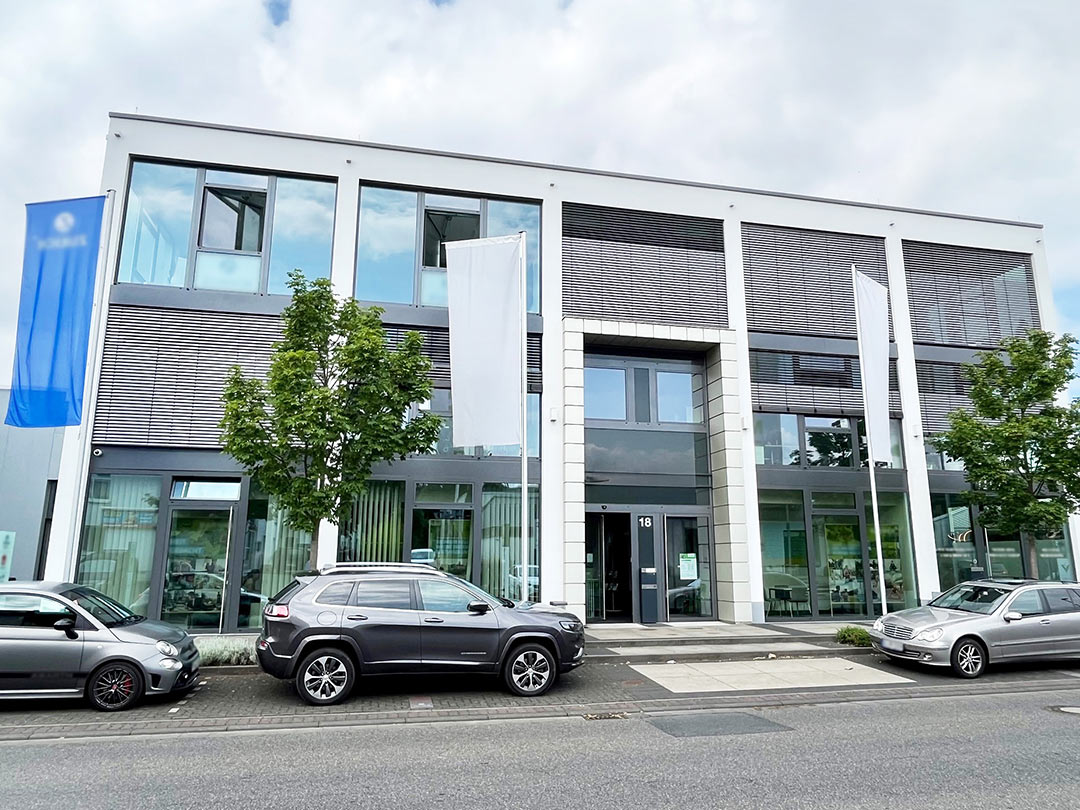 Modernes Bürogebäude mit Autos davor.