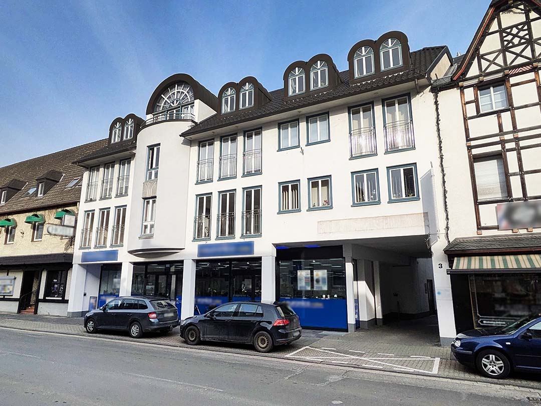 Mehrstöckiges Gebäude mit geparkten Autos davor.