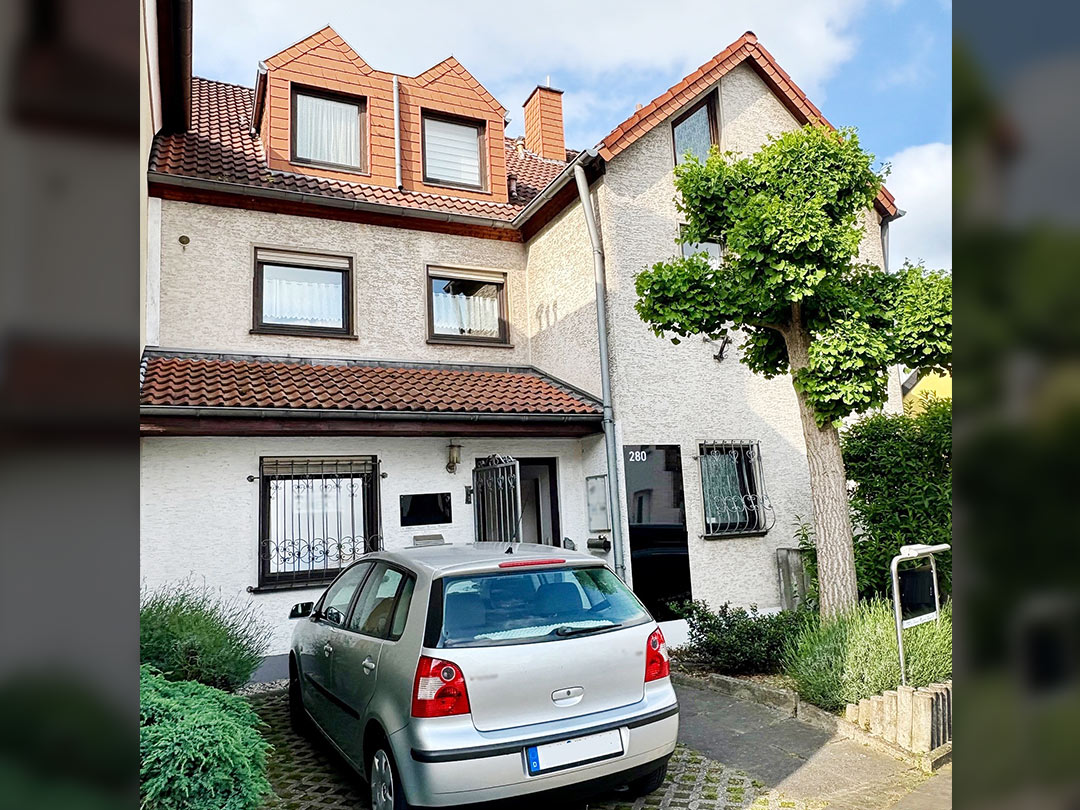 Zweistöckiges Haus mit geparktem Auto davor.