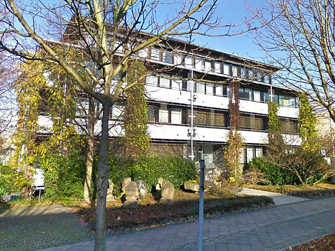 Modernes Gebäude mit Pflanzen und Bäumen.