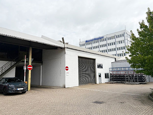 Industriegebäude mit Garagentor und Parkplatz.